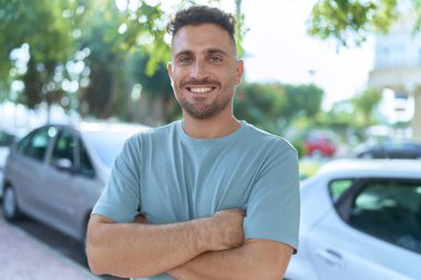 Sokakta kollarını kavuşturmuş İspanyol genç bir adam.