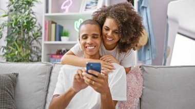 Kanepede oturan güzel bir çift evde akıllı telefon öpüşmesi yapıyor.