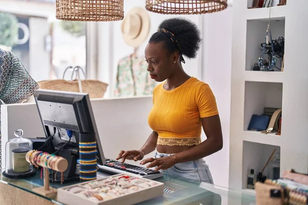 African american woman shop assistant using computer working at clothing store