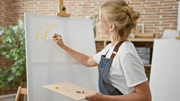 Young blonde woman artist drawing concentrated at art studio