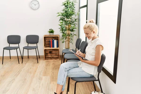 Junge Blonde Frau Sitzt Mit Smartphone Auf Stuhl Wartezimmer — Stockfoto