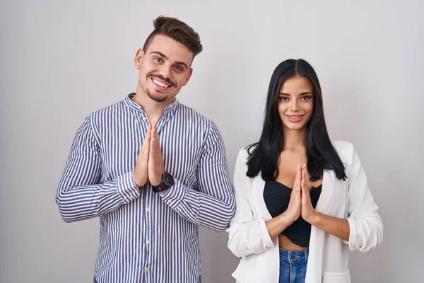 Young Hispanic Couple Standing White Background Praying Hands Together Asking — Stock Photo, Image