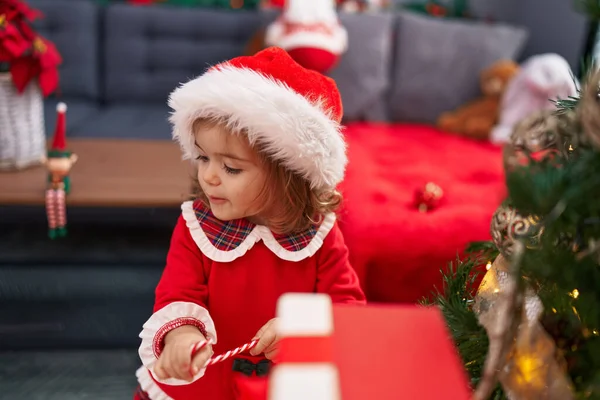 Sevimli sarışın bebek gülümsüyor. Evdeki kendine güvenen Noel ağacını süslüyor.