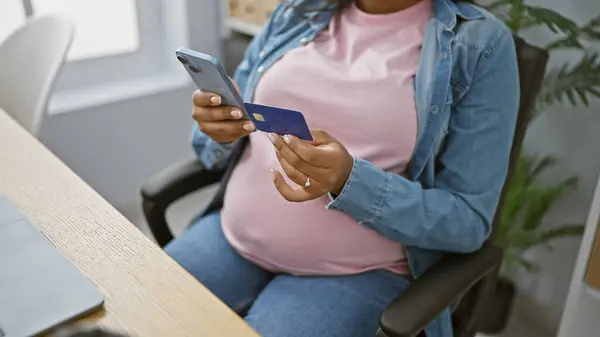 期待着年轻的专业人士 一个怀孕的女商人 用智能手机在她的办公室网上购物 用信用卡付款 — 图库照片