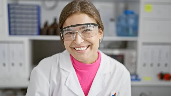 Charming young hispanic woman scientist, beaming with confidence and beauty, working in the lab, wearing safety glasses for optimum security.