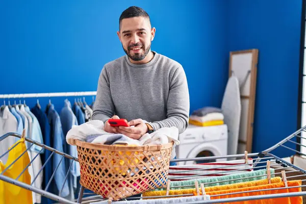 Young Latin Man Talking Smartphone Hanging Clothes Clothesline Laundry Room — Stock Photo, Image