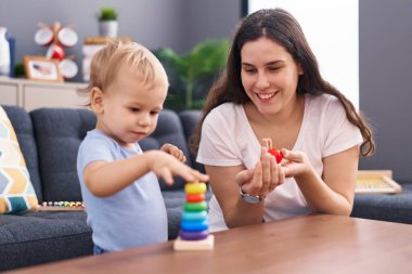 Anne ve oğlu evde oynarken kendinden emin gülümsüyor.