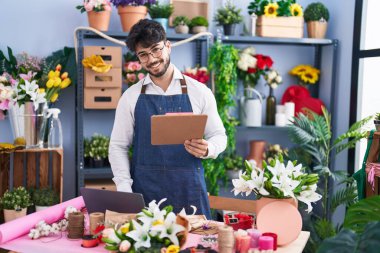 Çiçekçide dizüstü bilgisayar kullanarak kitap okuyan İspanyol bir çiçekçi.