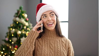 Genç, güzel, İspanyol bir kadın akıllı telefondan Noel 'i evde kutluyor.