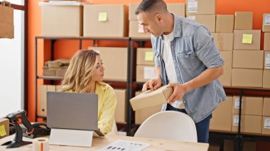 Kadın ve erkek dış ticaret işçileri ellerinde bir paketle ofiste konuşuyorlar.