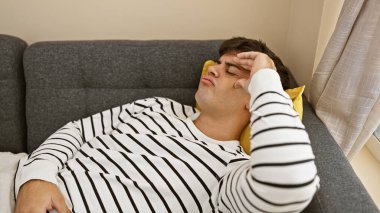 Stresli, yalnız, kaygıyla boğuşan genç bir İspanyol evdeki oturma odasındaki kanepesinde hayal kırıklığı ve üzüntünün portresi olarak yatıyor.