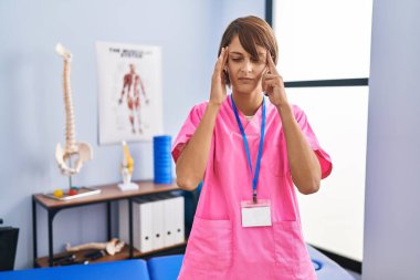 Esmer kadın rehabilitasyon kliniğinde çalışıyor. Stres yüzünden baş ağrısı çekiyor. migren ağrısı. 