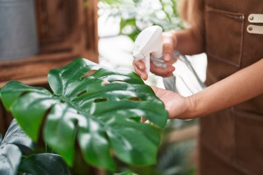 Young blonde woman florist using difusser working at flower shop