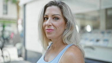 Sokakta kendine güvenen genç sarışın kadın gülümsüyor