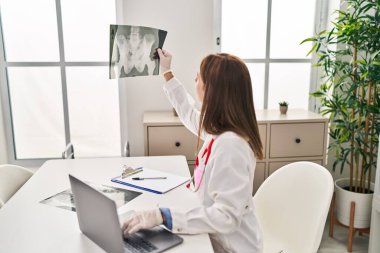 Genç sarışın doktor. Klinikteki masada oturuyor.