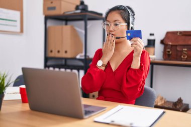 Asyalı genç bir kadın bilgisayar bilgisayarı ve kredi kartı kullanarak ağzını eliyle kapatıyor, şok geçiriyor ve hata yapmaktan korkuyor. şaşırmış ifade 