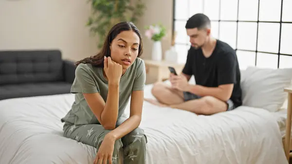 ベッドに座って スマートフォンを使用しながら葛藤を表現する彼らの寝室で同意しない美しいカップル 深刻な表現を引き起こす問題 — ストック写真