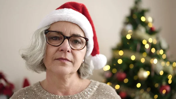 中年妇女 白发苍苍 一本正经地站在家里 头戴圣诞礼帽 — 图库照片