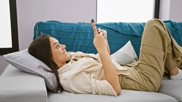 Cheerful Young Hispanic Woman Lying Sofa Home Expressing Surprise While — Stock Photo, Image