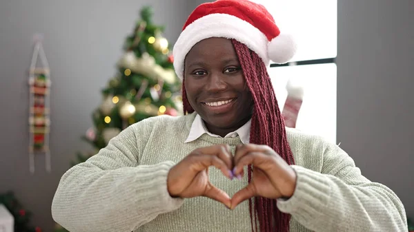 拥有辫子的非洲女人在圣诞树旁笑着 双手在家里做心形 — 图库照片