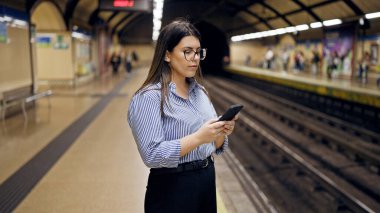 Madrid metro istasyonunda akıllı telefon kullanan güzel İspanyol bir kadın metroda bekliyor.