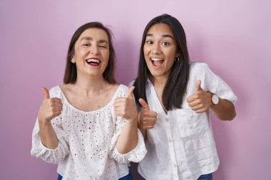 İspanyol anne ve kızı birlikte. Başarı işareti. Elleriyle olumlu jest yapıyor. Neşeli ifade ve kazanan jest. 
