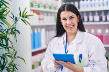 Eczanede çalışan dokunmatik ped kullanan genç, güzel İspanyol kadın eczacı.