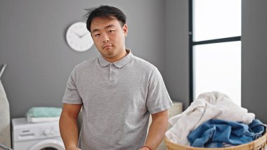  Çamaşır odasında rahat bir ifadeyle çamaşır ipinin yanında duruyor.