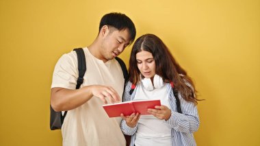 İzole edilmiş sarı arka planda kitap okuyan erkek ve kadın öğrenciler