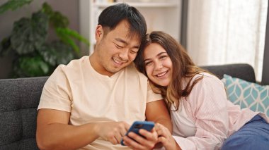 Erkek ve kadın çift evde akıllı telefon kullanıyor.