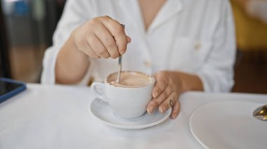 Lokantada masada kahve içen genç bir kadın.