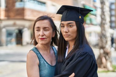 Two women mother and graduated daughter hugging each other at street