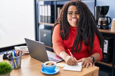 Ofiste dizüstü bilgisayar kullanarak çalışan Afrikalı Amerikalı kadın iş adamı.