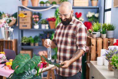 Çiçekçide çalışan genç ve kel bir çiçekçi.