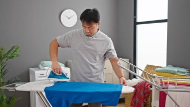  Çamaşırhanede rahat bir ifadeyle giysileri ütülüyor.