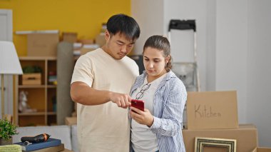 Yeni evde akıllı telefon kullanan erkek ve kadın.