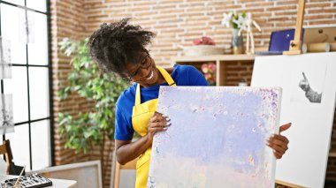 African american woman artist smiling confident holding draw at art studio
