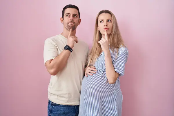 Casal Jovem Esperando Bebê Sobre Fundo Rosa Pensando Concentrou Sobre — Fotografia de Stock