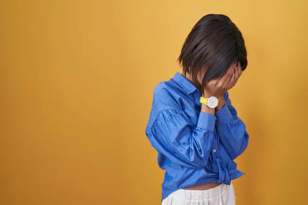 泣きながら手で顔を覆う悲しい表情で黄色の背景に立っている若い女の子 うつ病コンセプト — ストック写真