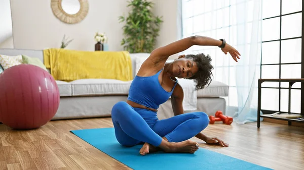 African american woman training yoga sitting on floor at home