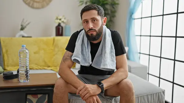 Young hispanic man sitting on sofa with serious face at home