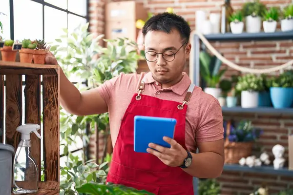 Young chinese man florist using touchpad at florist