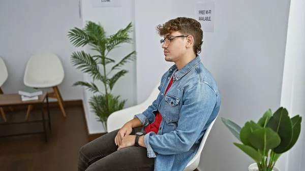 Neochvějně Mladý Hispánec Který Vážnou Tvář Zatímco Sedí Křesle Čekárně — Stock fotografie