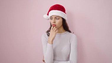 Genç, güzel İspanyol bir kadın. Üzerinde pembe bir arka plan ve fikir ifadesi olan Noel şapkası takıyor.