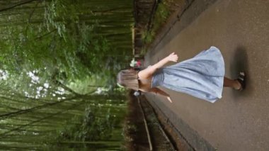 Gözlüklü neşeli İspanyol kadın dönüyor, güzel elbisesi Kyoto 'nun büyüleyici bambu ormanında akıyor.