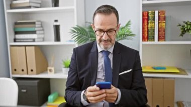 Gri saçlı, kendinden emin orta yaşlı bir adam. Ofis işinde mutlu mesut çalışıyor. Bu başarılı iş adamı masasında otururken akıllı telefonunu kullanıyor, pozitiflik yayıyor..