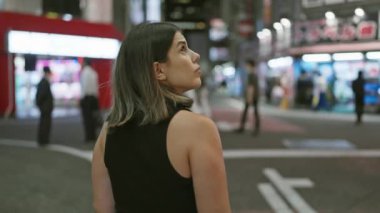 Güzel İspanyol kadın uzaklaşıyor, Tokyo sokaklarında geziniyor, gece ışıklarına geri dönüp bakıyor.