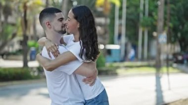 Kendine güvenen, güzel bir çift güneşli bir parkta kucaklaşıp neşeyle gülümsüyor, aşkı ve mutluluğu ifade ederken gündelik, açık hava yaşam tarzının tadını çıkarıyor..