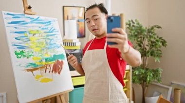 Gülümseyen genç Çinli sanatçı, stüdyodaki video görüşmeleri yoluyla sanat dersi veriyor.