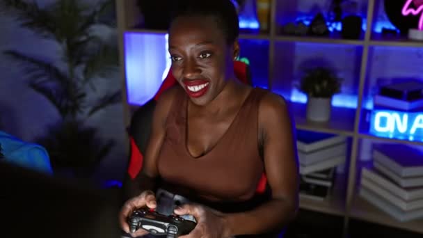 楽しいアフリカ系アメリカ人女性は 居心地の良い夜のゲームルームでゲームの成功を祝い 承認サインを示し 幸せな笑顔は自信を放射します — ストック動画